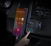 A hand is shown pressing a button on a car FM transmitter plugged into a car's power outlet, while a smartphone is connected to it. Anteprima dell’immagine prodotto