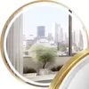 A round mirror with a gold frame reflecting a city view from a balcony. Voir les images du produit
