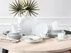 A table setting with a 30-piece white porcelain dinnerware set, including plates, bowls, and cups, arranged for display. Produktbild-Vorschau