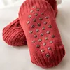 Paar rote gestrickte Anti-Rutsch-Socken mit dunkelbraunen Noppen auf den Sohlen, von unten gesehen Náhľad obrázku produktu