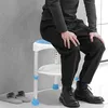 A person is sitting on a shower stool in a bathroom. Produktbild-Vorschau