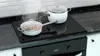 A stovetop with two pots on it, one of which is steaming. Podgląd zdjęcia produktu