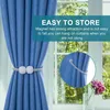 A blue curtain is held back by a magnetic tie-back with pearl-like beads. A close-up inset shows how the tie-back attaches. Text overlays describe the product's ease of storage. Produktbild-Vorschau