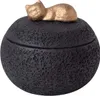 A black, textured, round lidded container with a gold cat figurine on top. Náhled obrázku produktu