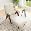 A cream-colored chaise lounge chair with wooden accents is placed on a patterned rug in a well-lit room with a large window. Náhled obrázku produktu