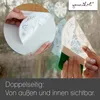 Hands applying window stickers to a glass surface, with a squeegee being used to smooth them down. The stickers feature winter-themed designs like snowflakes and Christmas trees. Produktbild-Vorschau