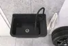 A black sink with a faucet is shown in a garage or workshop setting, with a tire and a towel nearby. Anteprima dell’immagine prodotto