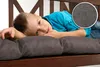 A young boy is lying on a cushioned bench, resting his head on his hands. A close-up of the fabric texture is shown in a circular inset. Produktbild-Vorschau