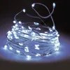 A coiled string of white LED micro lights on a dark background. Voir les images du produit