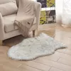 A fluffy white and gray rug is placed on a wooden floor next to a beige armchair with a fringed blanket draped over it.