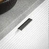 A close-up view of a white cabinet with a textured surface and a black handle. A gray fabric is draped over the top edge of the cabinet. Anteprima dell’immagine prodotto
