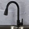 A black kitchen faucet with a pull-out spray head is shown in front of a gray marble-patterned backsplash and a stainless steel sink. Produktbild-Vorschau
