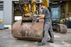 A man is using a cordless impact wrench to work on the bucket of an excavator in a workshop. Voir les images du produit