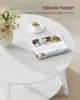 A white round coffee table with a magazine and a cup of coffee on it. Produktbild-Vorschau