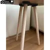 Close-up view of the wooden legs of a table attached to a black fixture. Produktbild-Vorschau