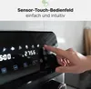 A hand is shown interacting with the touch control panel of a black kitchen appliance, likely an air fryer, with digital displays showing time and settings. Voir les images du produit