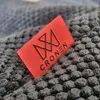 A close-up of a red label with a logo and text on a textured gray surface. Náhľad obrázku produktu