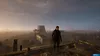 A person stands on a rooftop overlooking a misty, post-apocalyptic landscape with industrial structures in the distance. Produktbild-Vorschau
