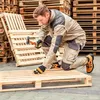 A man is working on a wooden pallet. Produktbild-Vorschau
