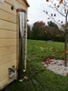 A stainless steel chimney pipe attached to a wooden structure, with a grassy yard and trees in the background. Anteprima dell’immagine prodotto