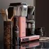 A pink Moccacoffee machine with accessories on a kitchen counter. Náhľad obrázku produktu