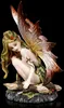 A fairy figurine sitting on a log.