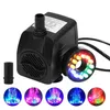 A black submersible water pump with a ring of colorful LED lights is shown against a white background. Several smaller circular images below show the pump in action, creating water fountains illuminated by different colored lights. Produktbild-Vorschau