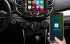 A person's hand holds a smartphone displaying the CarPlay interface, which is connected to a car's infotainment system. Produktbild-Vorschau
