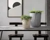 Two planters with plants on a wooden table in front of a framed artwork. Anteprima dell’immagine prodotto
