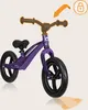 A purple balance bike with an orange arrow indicating handlebar movement and a lock icon. Produktbild-Vorschau