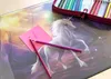 A desk mat with a unicorn design, two colored pencils, and a pink sticky note. Náhľad obrázku produktu