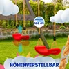 Two red swings hanging from a wooden swing set in a garden, with decorative clouds and text overlays. Produktbild-Vorschau