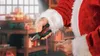 Santa Claus is holding pliers and a wire in a workshop setting. Produktbild-Vorschau