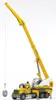 A yellow and white Bruder MACK Granite Liebherr crane truck is shown against a white background, with a gray object being lifted by the crane. Náhľad obrázku produktu