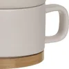 A close-up view of a ceramic mug with a bamboo base. Podgląd zdjęcia produktu