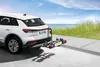 A white car with a bike rack attached is parked on a paved surface near a beach. Produktbild-Vorschau