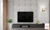 A modern living room with a TV mounted on a textured wall, a media console, and decorative elements. Produktbild-Vorschau