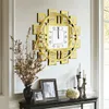 A decorative wall clock with Roman numerals is displayed on a wall above a console table with framed pictures and candles. Voir les images du produit