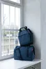 Two blue duffel bags are stacked on a windowsill next to a window. Voir les images du produit