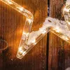 A close-up of a star-shaped string light with snow on it, set against a wooden background. Produktbild-Vorschau