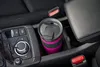 A travel mug sits in the cup holder of a car, next to the center console and armrest. Anteprima dell’immagine prodotto
