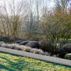 A garden scene in winter with frost on the plants and grass, featuring a metal garden edging. Voir les images du produit