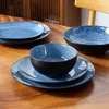 A set of blue ceramic dishes on a wooden table. Voir les images du produit
