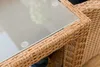 A close-up view of the corner of a wicker table with a glass top. Náhled obrázku produktu