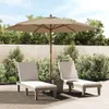 Two lounge chairs and a patio umbrella are set up on a paved patio area, surrounded by lush green bushes and trees. Produktbild-Vorschau