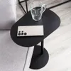 A black metal side table with a smartphone and a glass mug on it, next to a gray sofa. Voir les images du produit