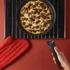 A hand holding a pan handle, with a cookie dough in a pan on an oven rack, and an oven mitt nearby. Anteprima dell’immagine prodotto