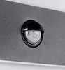 A close-up of a motion sensor on a textured gray surface, with a white border at the top and bottom. Produktbild-Vorschau