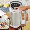 A hand presses a button on a Moulinex Easy Soup maker, with mugs and a magazine on a wooden table. Produktbild-Vorschau