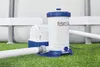 A pool filter pump system is shown on a grassy surface next to an above-ground swimming pool. Voir les images du produit